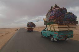 Western Egyptian desert road, pick up trucks fully/over loaded.