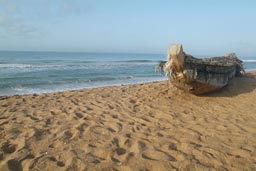 Grand Popo, morning pirogue, fishing boat, sitting on sand. Sea behind