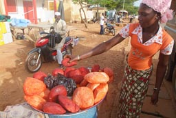 Black girl selling arange goats cheese in Natingou, Benin.