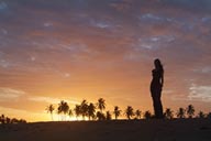 Sunset dance on beach, palm trees in red sky, girl dancing on beach.