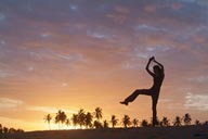 Sunset dance on beach, palm trees in red sky, girl dancing on beach.