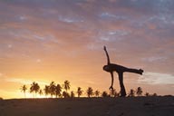 Sunset dance on beach, palm trees in red sky, girl dancing on beach.