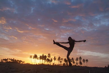 Sunset dance on beach, palm trees in red sky, girl dancing on beach.