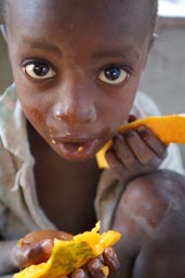 African boy eating Papaya, face full of yellow squash, Guinea Bissau.