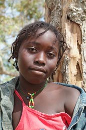 Daughter of Marie Toure, face of African girl, red blouse, jeans jacket, no smile, Guinea Bissau.