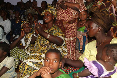 Crowd watching, clapping, feeding babies.