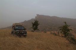 Bushcamp Land Rover in front of Dogon falaises/cliffs, Harmattan think sky.