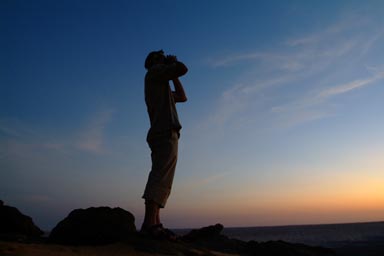 Robert with binoculars watching direction sunset