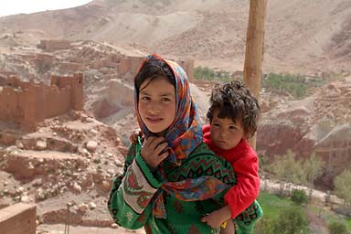 young girl carrying her brother on road Talouet to Ait-Benhaddou