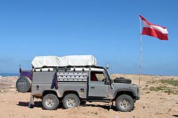Land Rover Defender 6x6 on Tifnit beach with Austrian flag.