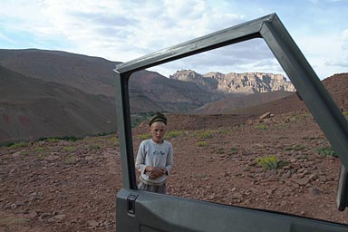 Boy and M'Goun through door of Land Rover