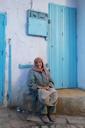 Chefchaouen, alley blue and white, old woman in front of blue door