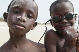 Posing teen African boys on the beach, sand on their faces.