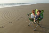 Twins on beach on a chair surrounded by the sea, in Djembering, southern Senegal, Casamance.