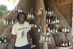 Christopher from bar/Restaurant Africando on Karabane, Silk Cotton Tree serves as shelf.