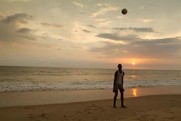 Lumley beach, Aberdeen, Freetown, Sierra Leone, footballer on beach, sunset behind.