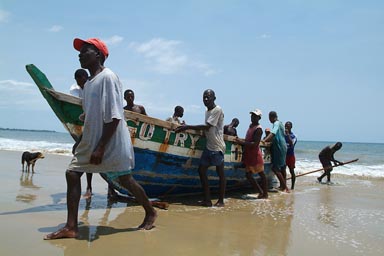 Fishermen boat, pirogue being pulled/pushed up on Lumley beach, Aberdeen, Freetown, Sierra Leone.