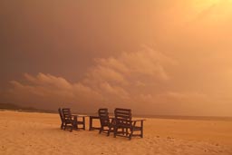 Deck chairs on beach, yellow clouds.