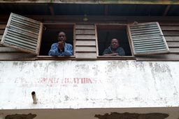 Jonestone and friend, in his hotel looking through wooden window, Buchanan, Liberia.
