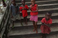 4 African children dressed in red on church steps.