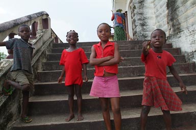 Harper, Liberia, 4 African children dressed in red on church steps.
