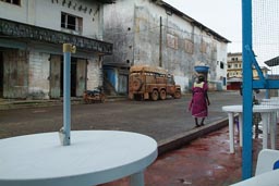 Harper, Maryland, Liberia, sit at sophie's spot cafe in mechlin street, 6x6 Land Rover Defender parked on other side, African woman with load on her head walks by, white plastic chairs and tables.