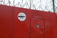 Harper, Maryland, Liberia, red iron door with no guns sign, barbed wire.