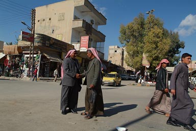 Syrian men wearing the Keffiyeh shake hands in street.