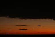 New new-moon, on orange sky, black clouds above and below. New new-moon, on orange sky, black clouds above and below.