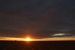 Sun under clouds, Syrian desert, road, car. Before sunset.