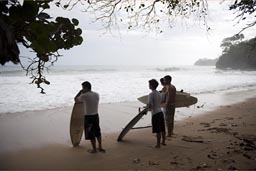 Surfers looking out on Caribbean Sea, Manzanillo, Costa Rica.