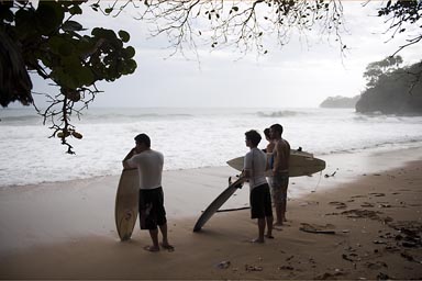 Brazillian surfers watch the waves on lone beach, Caribbean Costa Rica.