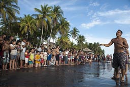 Guy from turtle hatchery explains how the tutle race works. El Zonte and palms on beach. line of children and turtles in hands, El Salvador.