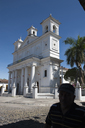 Suchitoto, El Salvador. Shadow/silhuette of man in front of white church and blue sky.
