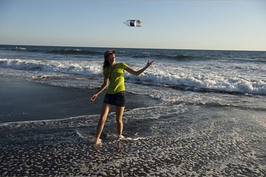 C. in mini jeans skirt and green t-shirt, throwing a 2l water bottle on a Guate beach..