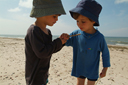 Boys in hats, watching a bug on a stick.