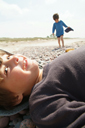 Daniel lies down, smiles, David in back. Beach in Latvia.