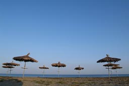 Parasols of straw on beach in Larnaca, Cyprus, Clear blue evening skies.