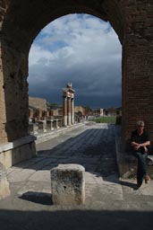 Pompeii, tourist, arch and columns, bad weather clowds.