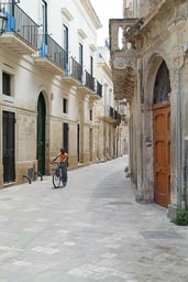 Lecce, Puglia, little lane, African boy on bicycle.