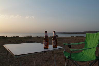 Near San Vito lo Capo, Camp, 2 Peroni, chair and table, sea and sunset in back.