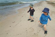 Twins and hats, run on beach, Latvia.