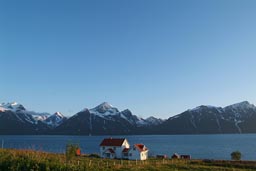 Lyngen mountains and fjord, Nowegian house in midnight sun.