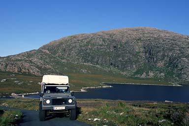 Land Rover on steep road near a loch