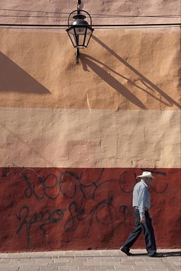 Morelia, a man with hat walks by a colorful house facade.