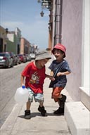 Twin boys laugh and play with a waterbottel in street of Campeche, Mexico. Series of 4 pictures.