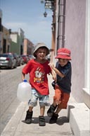 Twin boys laugh and play with a waterbottel in street of Campeche, Mexico. Series of 4 pictures.