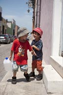 Twin boys laugh and play with a waterbottel in street of Campeche, Mexico. Series of 4 pictures.