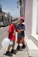 Twin boys laugh and play with a waterbottel in street of Campeche, Mexico. Series of 4 pictures.