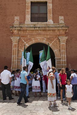 Maxcanu, Sunday. People in traditional white dress and Mexican flags outside church. Yucatan.